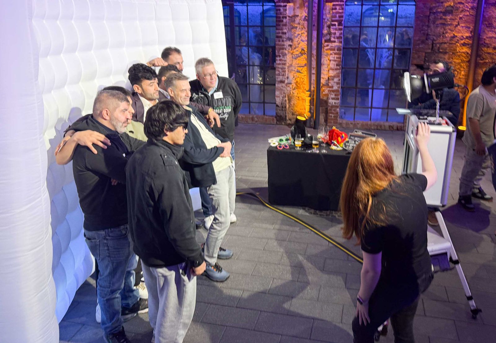 Klassik-Fotobox-Einsatz in der Industriekathedrale Alte Schmelz St. Ingbert — Männergruppe mit Sonnenbrillen-Requisiten vor Industriestein-Mauerwerk im lila Eventlicht