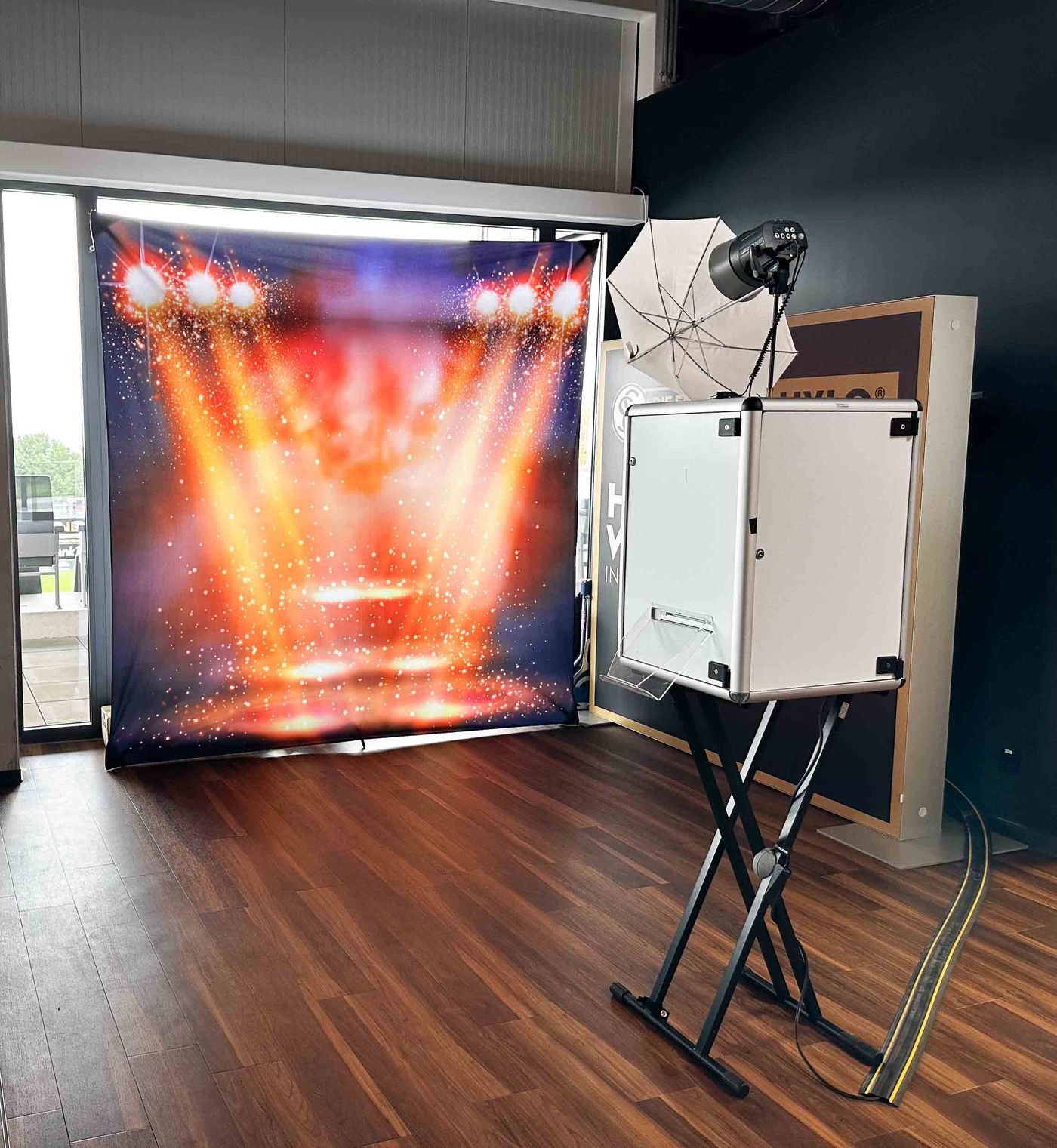 Foto Lutz Profi-Fotobox im VIP-Bereich der Ursapharm Arena Elversberg — weiße Box mit Sublimationsdrucker auf Stativ, Studio-Reflektor und Konzert-Backdrop mit Lichtshow