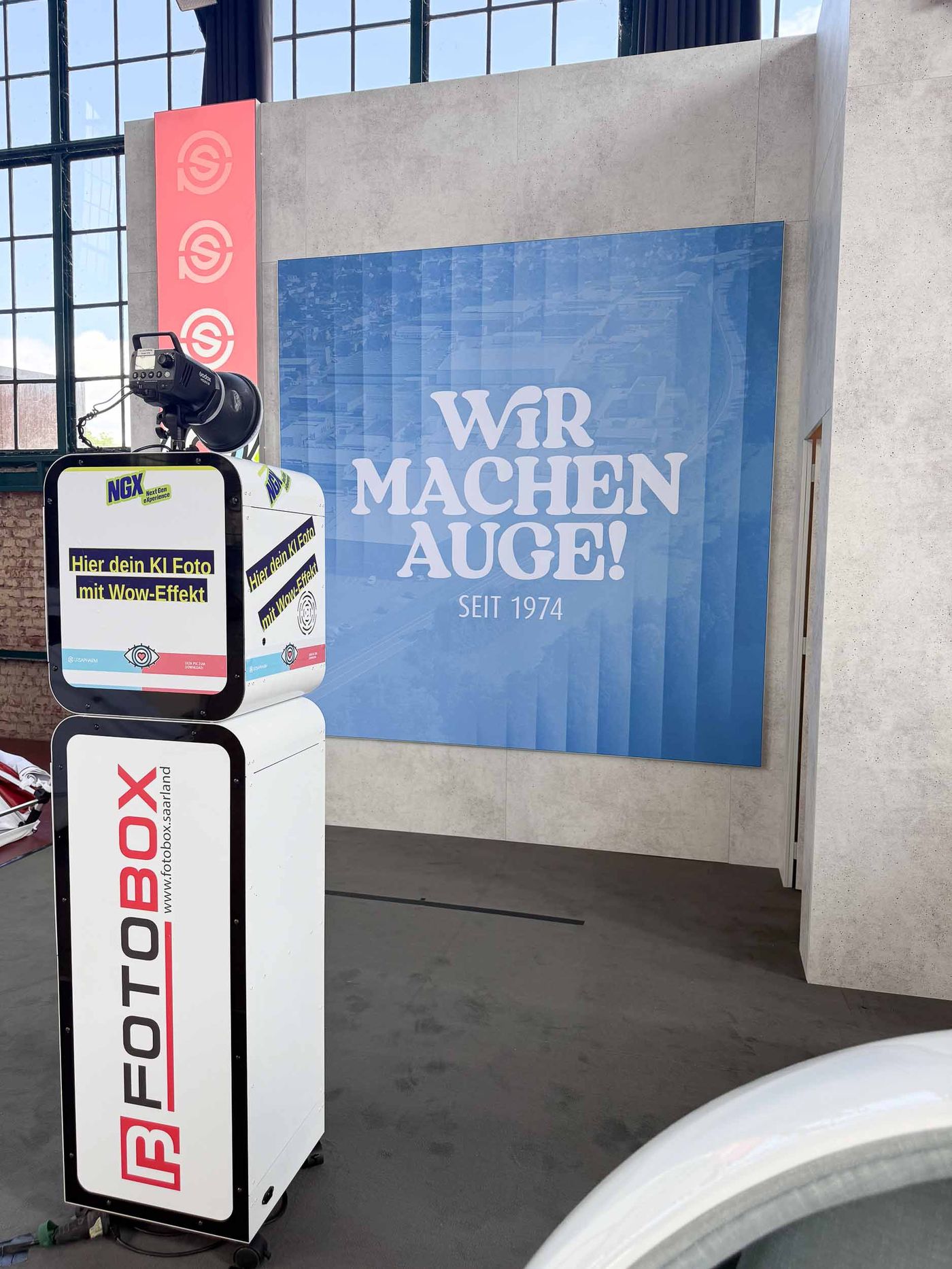 KI-Fotobox von Foto Lutz bei der NextGen eXperience am Ursapharm-Stand im E-Werk Saarbrücken — Hier dein KI-Foto mit Wow-Effekt Display, Ursapharm-Branding, Wir machen Auge seit 1974 Backdrop