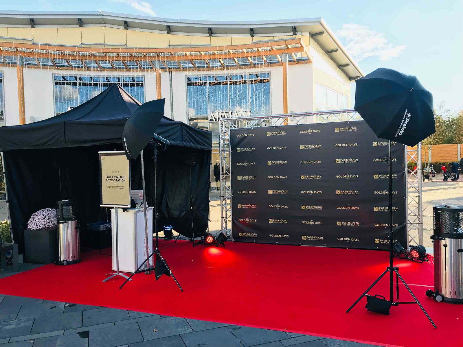 Foto Lutz Hollywood-Foto-Station und Fotoprintmodul im Fashion Outlet Center Zweibrücken — Outdoor-Pavillon-Setup auf rotem Teppich mit Studio-Schirmen und GOLDEN DAYS Eventbranding