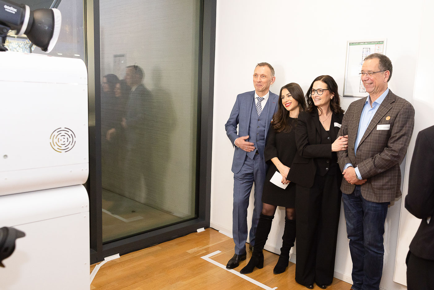 Eventgäste in eleganter Garderobe stehen vor der KI-Fotobox beim Neujahrsempfang