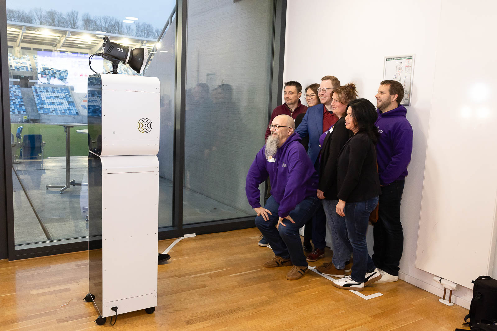 Team in einheitlichen Pullovern posiert vor der KI-Fotobox — auch große Gruppen passen ins Bild