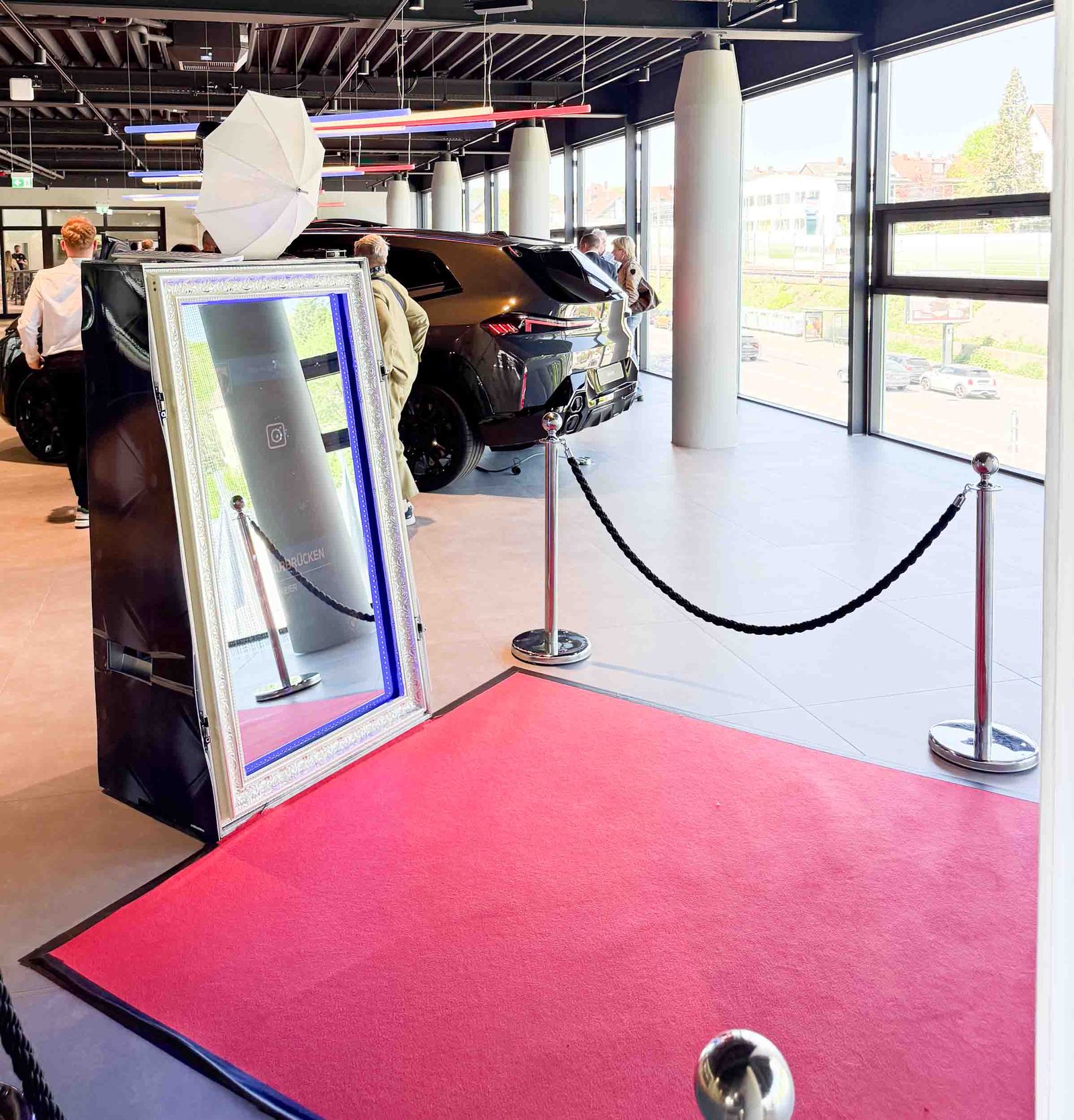 Magic Mirror Fotospiegel im BMW-Showroom — weißer Barockrahmen, roter Teppich, schwarze Absperrkordel und BMW-Fahrzeug im Hintergrund