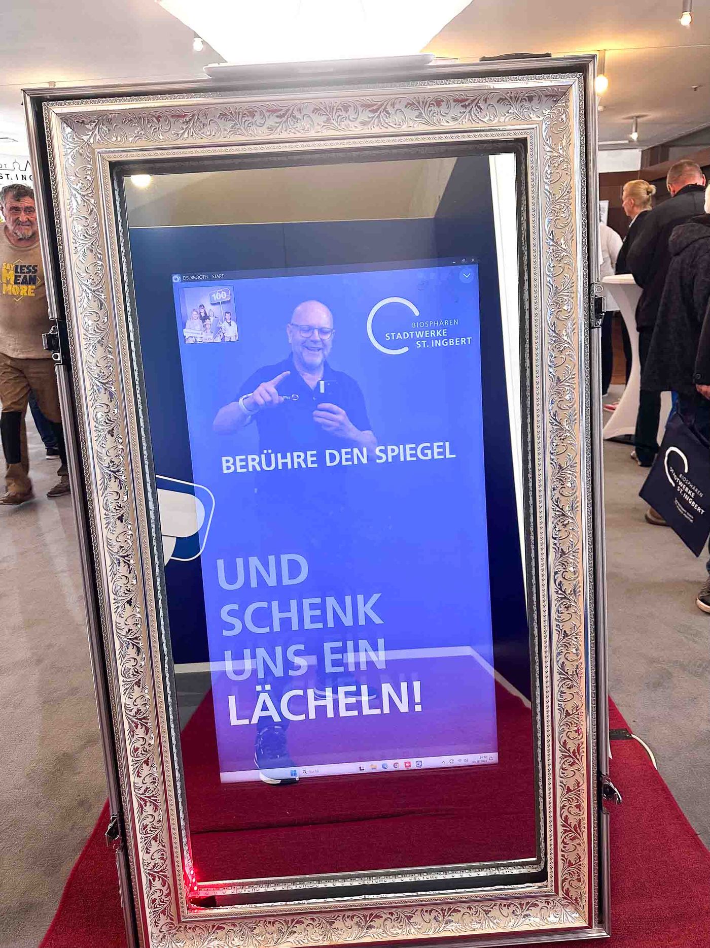 Magic Mirror Fotospiegel mit aktiver Touchscreen-Animation BERÜHRE DEN SPIEGEL UND SCHENK UNS EIN LÄCHELN im Stadtwerke-St-Ingbert-CI, goldener Barockrahmen