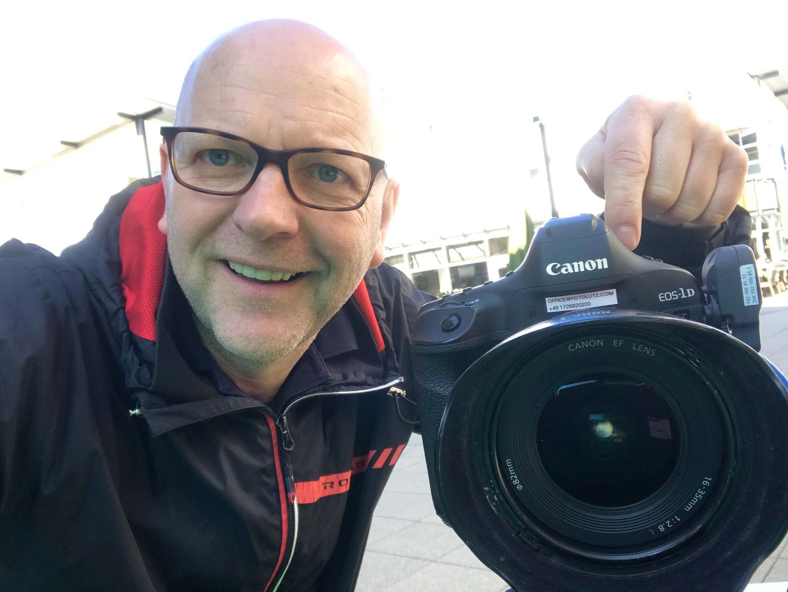Markus Lutz Selfie mit Canon EOS-1D Spiegelreflex-Kamera mit office@fotolutz.com Aufkleber, Fashion-Outlet-Zweibrücken im Hintergrund