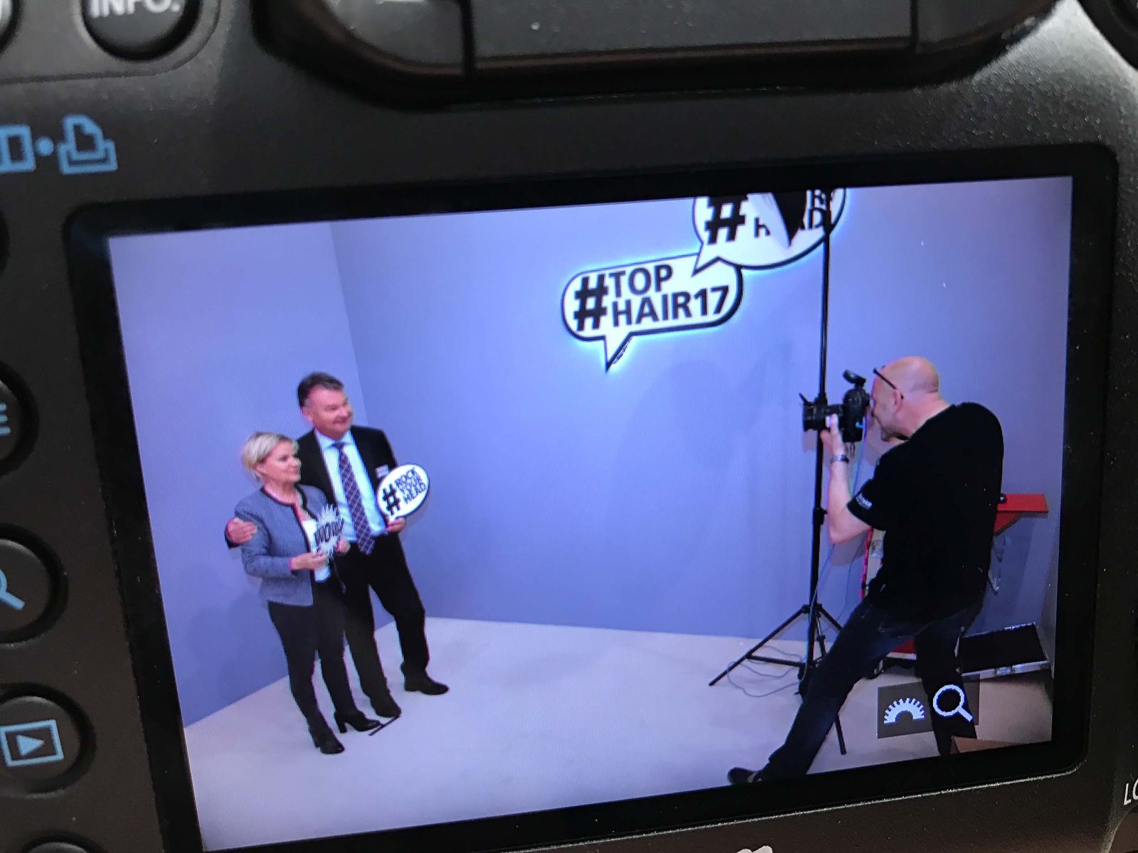 Markus Lutz live in Aktion bei der Tophair 2017 Messe — Foto von Camera-Display mit Gästen mit ROCK YOUR HEAD Schildern vor #TOPHAIR17 Sprechblasen-Backdrop